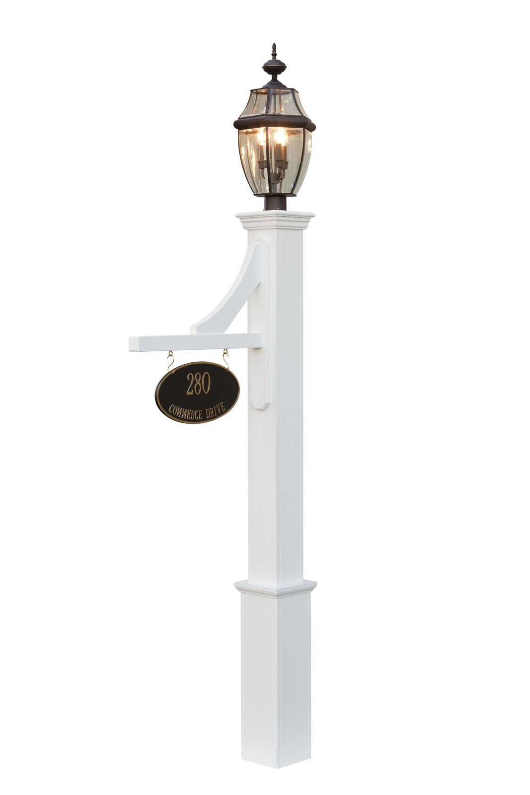 Lit Frankfort lamp post in front of a stone house at dusk