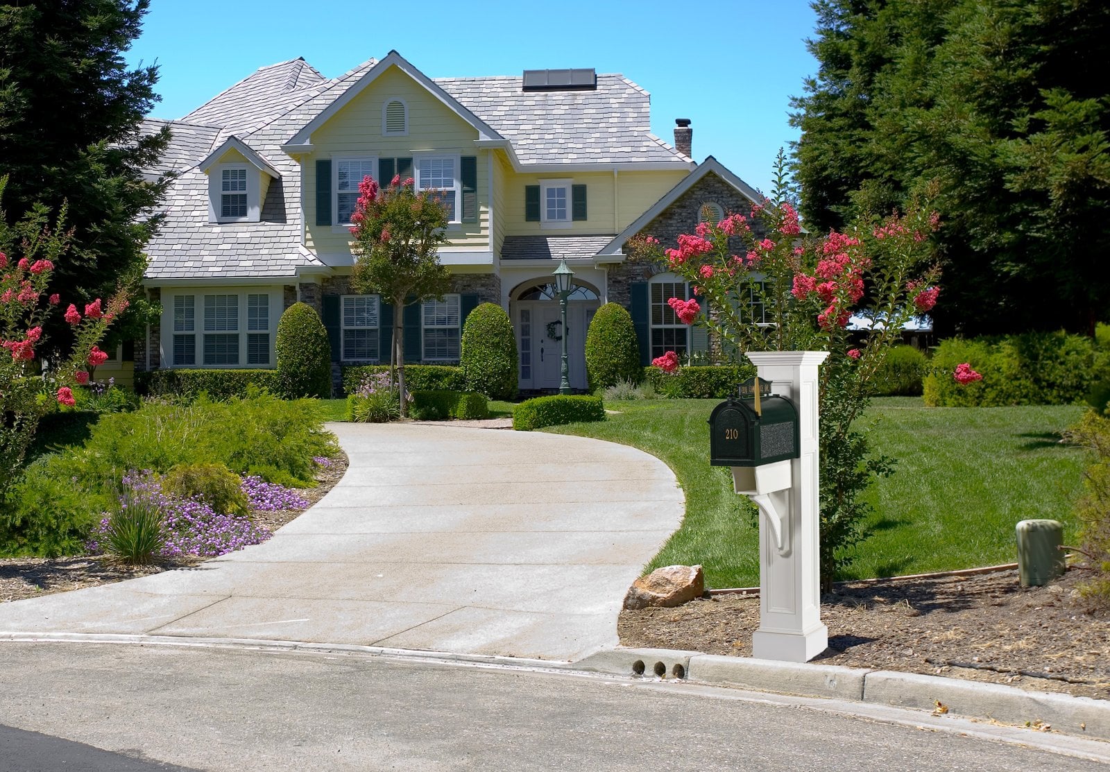 White Providence mailbox post with a green mailbox at the end of a curved driveway