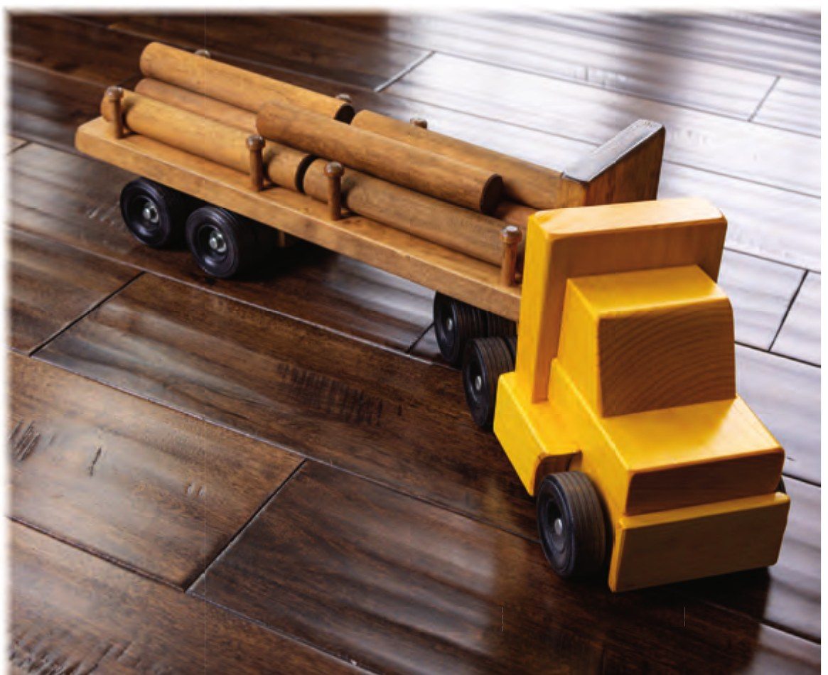 Yellow wooden log truck loaded with logs on a wood floor