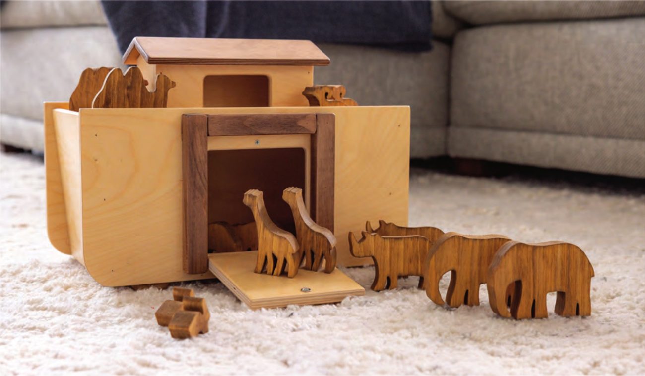 Wooden Noah's Ark with ramp door open and wooden animals on a rug